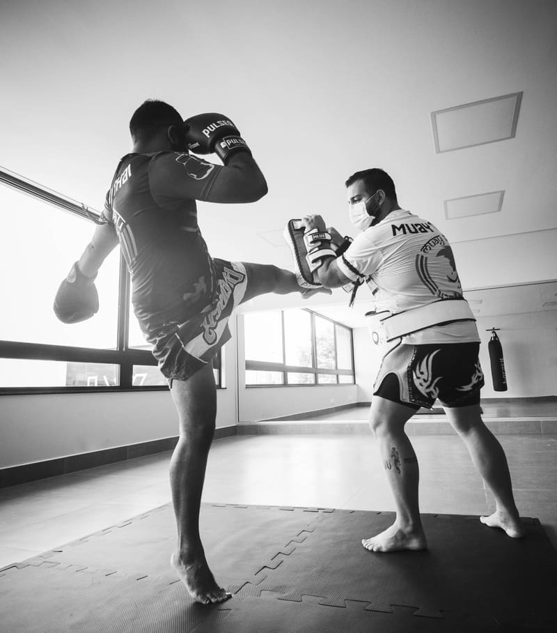Muay Thai athlete practicing a kick with a pad holder
